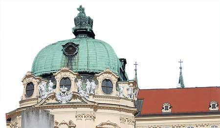 Reichskrone und Herzogshut thronen auf den Kuppeln des Augustiner-Chorherrenstifts Klosterneuburg, Doppeladler und Kaiserkrone über dem Hauptportal. Zeugen einer historischen Verbindung von Staat und Kirche, Politik und Religion.