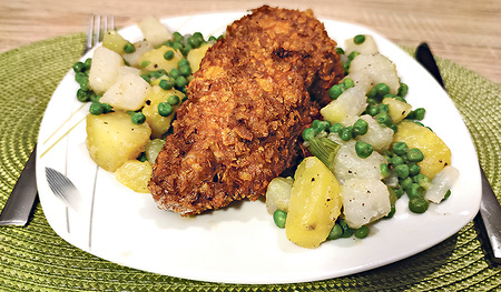 Das Gewürzbackhendl mit Cornflakespanier wird auf Kohlrabigemüse angerichtet.